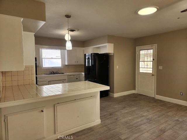 kitchen featuring backsplash, white cabinets, sink, decorative light fixtures, and tile counters