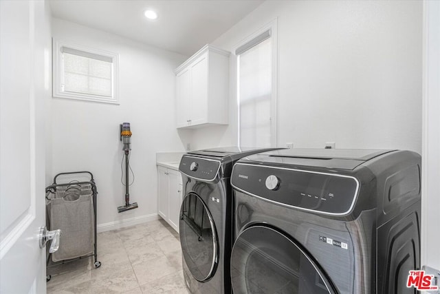 washroom with washing machine and dryer, cabinets, and light tile patterned flooring