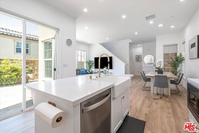 kitchen with stainless steel dishwasher, sink, light hardwood / wood-style flooring, an island with sink, and white cabinets