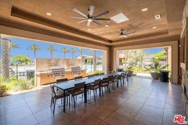 view of patio / terrace with ceiling fan, exterior bar, an outdoor kitchen, and area for grilling