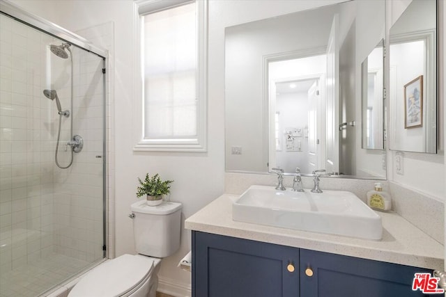 bathroom with toilet, vanity, and a shower with shower door