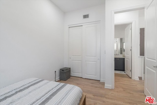 bedroom featuring light wood-type flooring, a closet, and ensuite bath