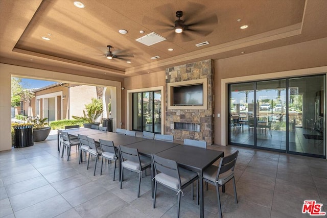 view of patio featuring ceiling fan, exterior bar, and an outdoor stone fireplace