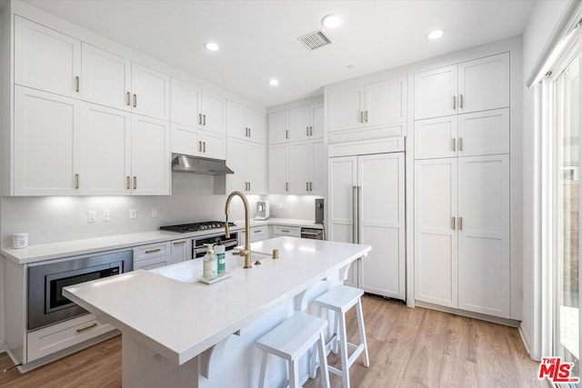 kitchen with a kitchen breakfast bar, white cabinets, and built in appliances