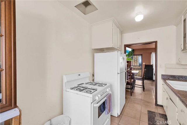 kitchen with white cabinets, light tile patterned floors, white appliances, and sink