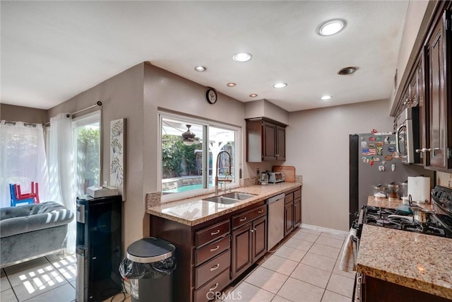 kitchen with light stone counters, sink, dark brown cabinets, and appliances with stainless steel finishes