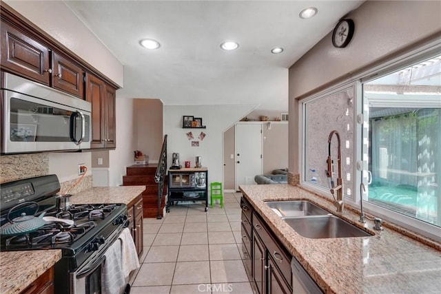 kitchen featuring sink, light stone countertops, light tile patterned floors, dark brown cabinetry, and stainless steel appliances