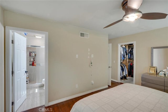 bedroom with ensuite bath, ceiling fan, a spacious closet, dark hardwood / wood-style flooring, and a closet