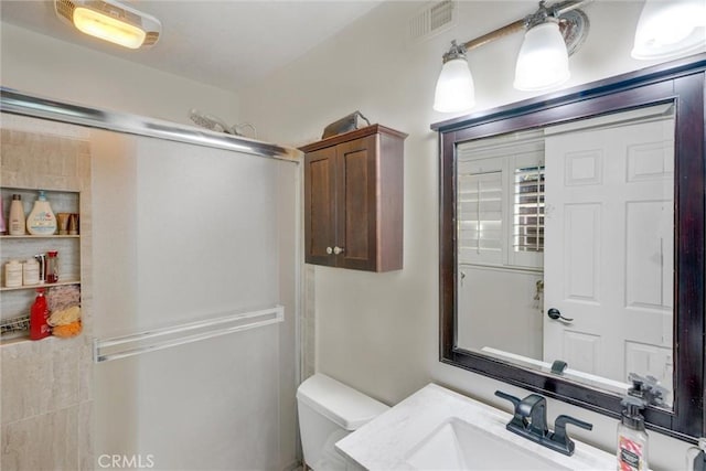 bathroom featuring vanity, toilet, and walk in shower