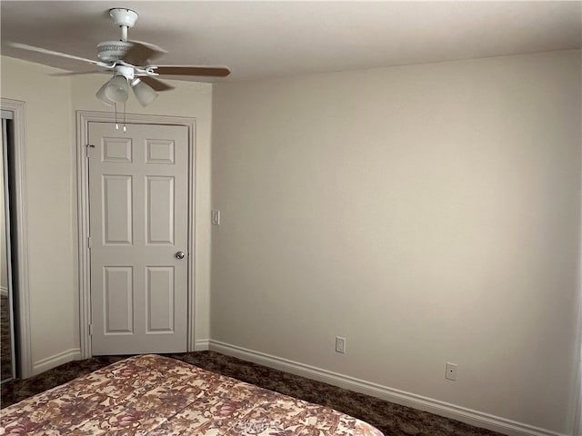 unfurnished bedroom with ceiling fan and dark colored carpet