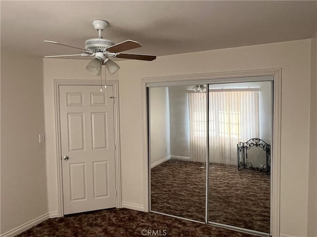 unfurnished bedroom featuring dark carpet, a closet, and ceiling fan