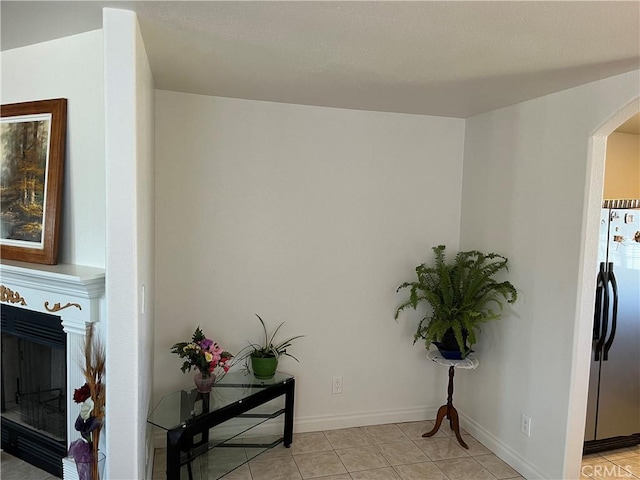 interior space with baseboards, a fireplace, freestanding refrigerator, and arched walkways