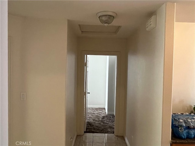 hall with baseboards, light carpet, and light tile patterned floors