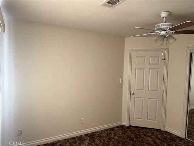 unfurnished room featuring baseboards, a ceiling fan, visible vents, and dark carpet