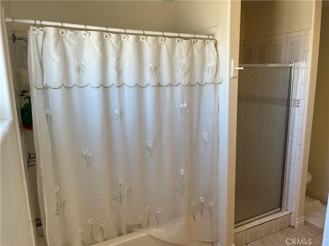 bathroom featuring a tub to relax in, a shower with curtain, tile patterned flooring, and toilet