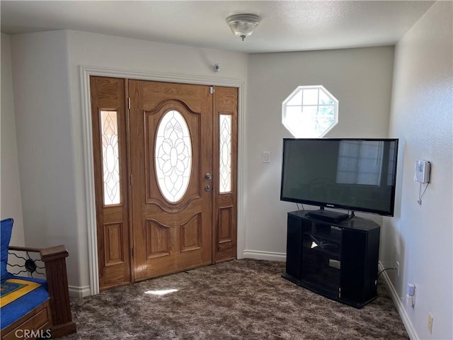 foyer with dark carpet, plenty of natural light, and baseboards