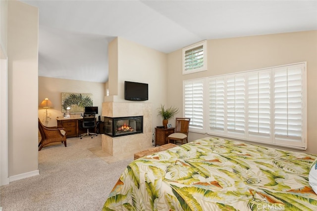 carpeted bedroom featuring vaulted ceiling and a tiled fireplace