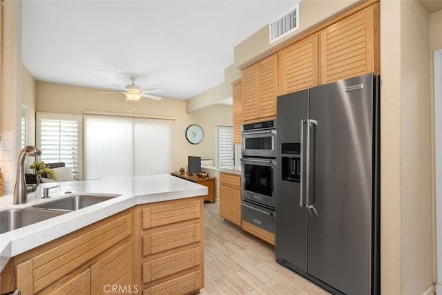 kitchen with sink, light wood-type flooring, stainless steel appliances, and a wealth of natural light