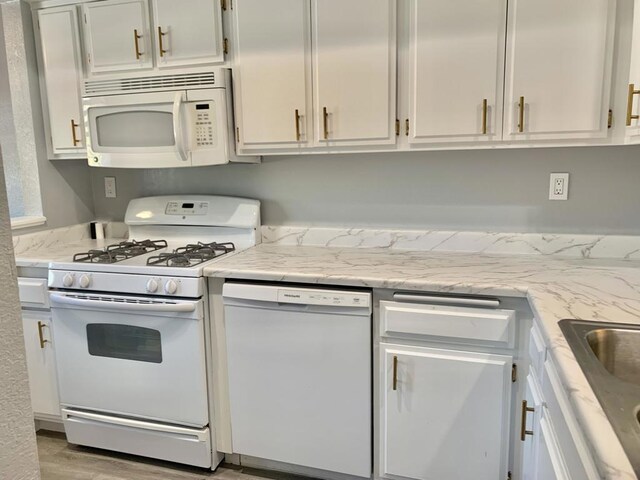 kitchen with light stone countertops, white appliances, light hardwood / wood-style flooring, and white cabinets