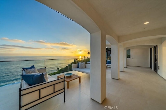 balcony at dusk featuring outdoor lounge area and a water view