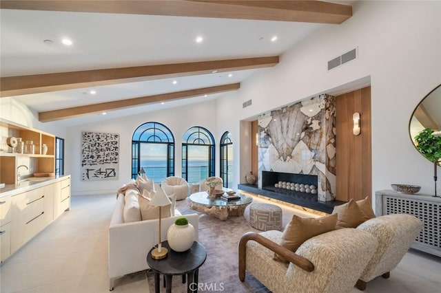 living room featuring radiator heating unit, a high end fireplace, lofted ceiling with beams, and sink