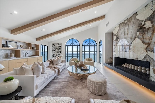 living room with vaulted ceiling with beams, light tile patterned floors, and sink