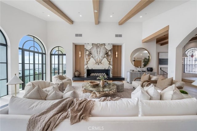 living room featuring a wealth of natural light, beamed ceiling, and a high ceiling