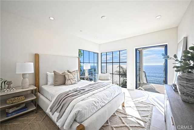 bedroom featuring access to outside, multiple windows, and a water view