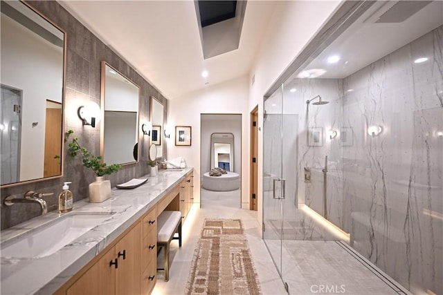 bathroom with vanity, vaulted ceiling, a shower with door, and tile walls