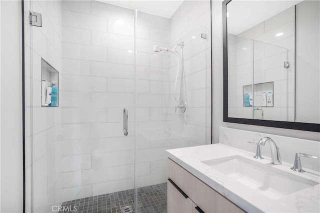 bathroom featuring a shower with shower door and vanity