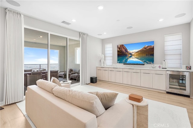 living room featuring indoor wet bar, wine cooler, and light hardwood / wood-style floors