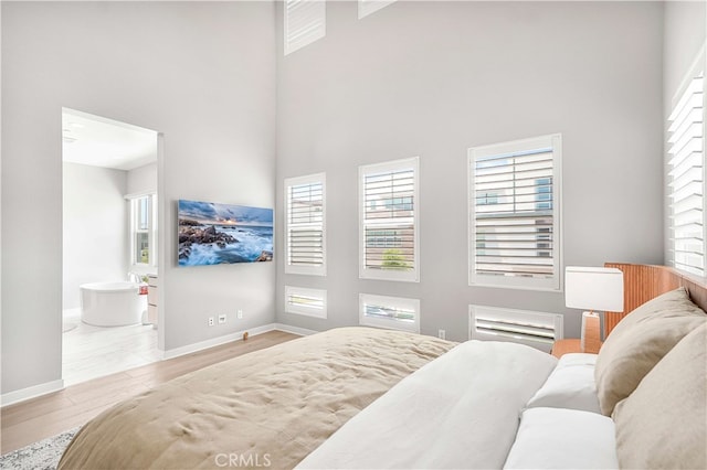 bedroom with light hardwood / wood-style floors and a high ceiling