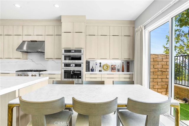 kitchen featuring appliances with stainless steel finishes, a breakfast bar area, and wall chimney range hood