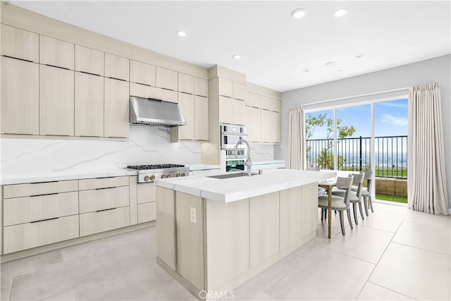 kitchen featuring tasteful backsplash, sink, range hood, an island with sink, and appliances with stainless steel finishes