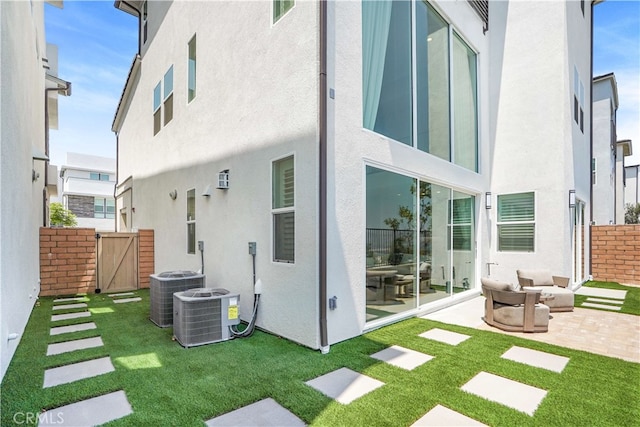 rear view of property with cooling unit, a yard, and a patio