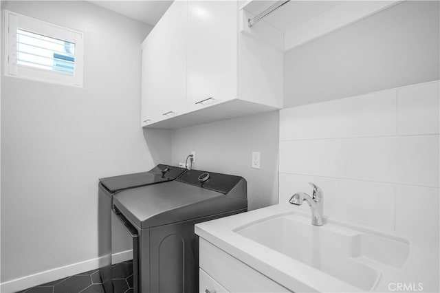 laundry room featuring cabinets, dark tile patterned floors, sink, and washing machine and dryer