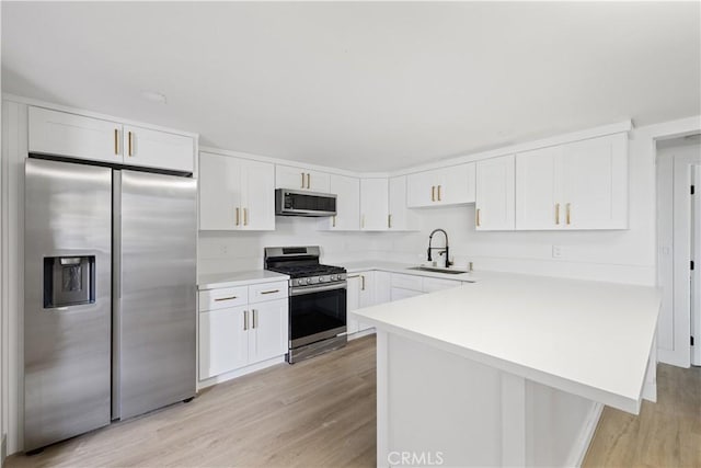 310 Whittley Ave Unit A, Avalon, CA 90704 - kitchen featuring light countertops, light wood finished floors, appliances with stainless steel finishes, white cabinetry, and a sink