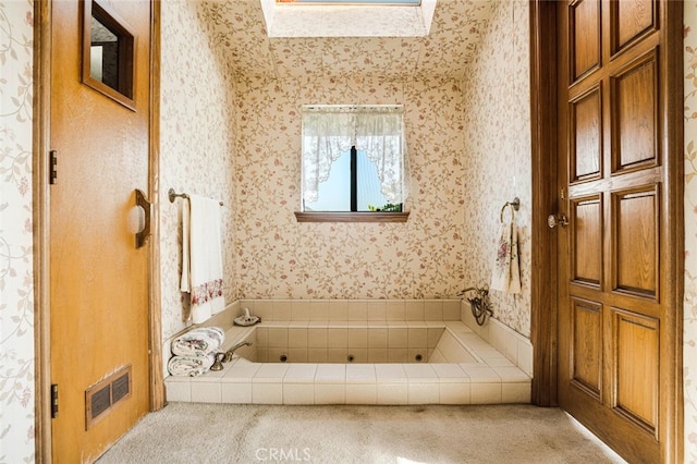 bathroom with a skylight and a tub