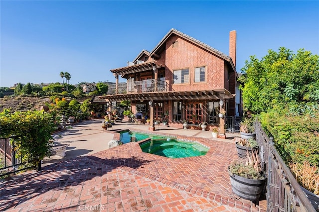 rear view of house with a swimming pool with hot tub, a pergola, and a patio area