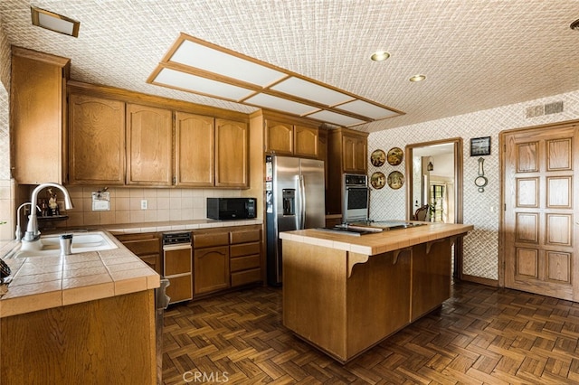 kitchen featuring sink, a kitchen island, appliances with stainless steel finishes, dark parquet floors, and butcher block countertops