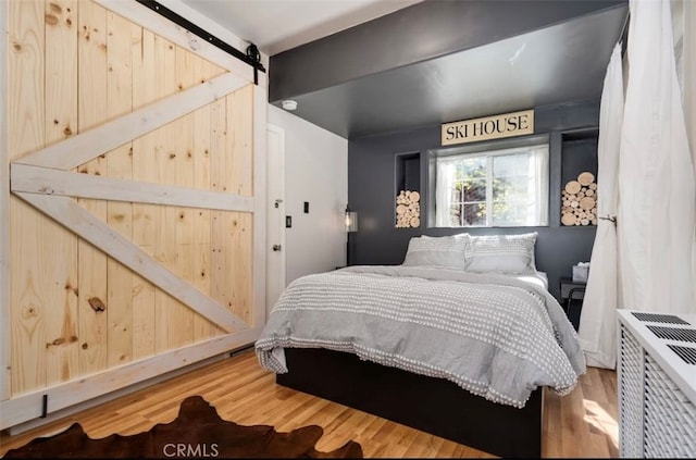 bedroom featuring a barn door and hardwood / wood-style flooring