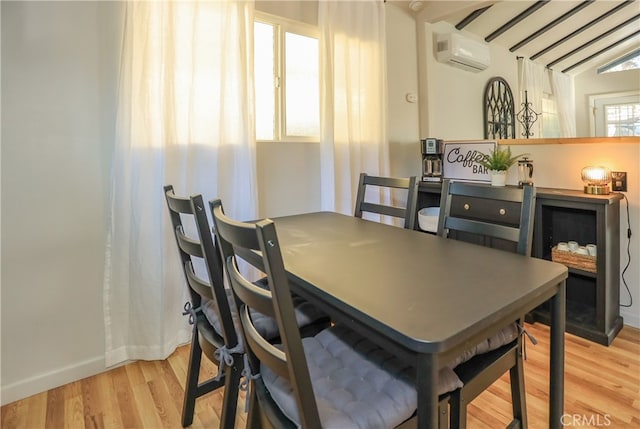 dining area featuring light hardwood / wood-style floors, a wall unit AC, and vaulted ceiling