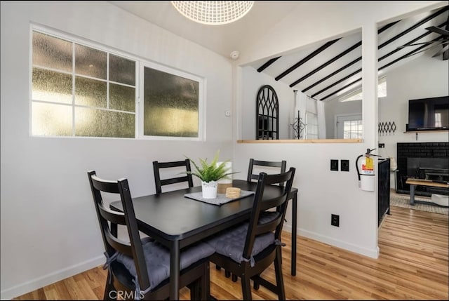 dining space with hardwood / wood-style flooring, vaulted ceiling, and a fireplace