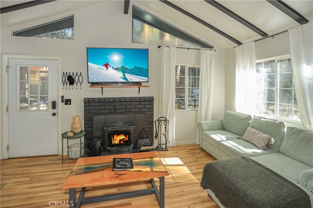 living room with lofted ceiling with beams, a brick fireplace, and light wood-type flooring