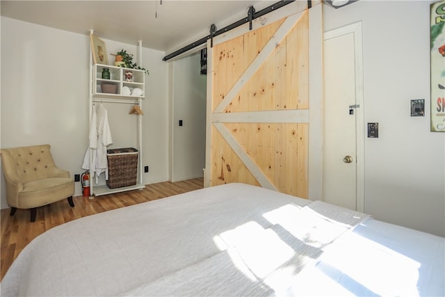 bedroom with hardwood / wood-style floors and a barn door