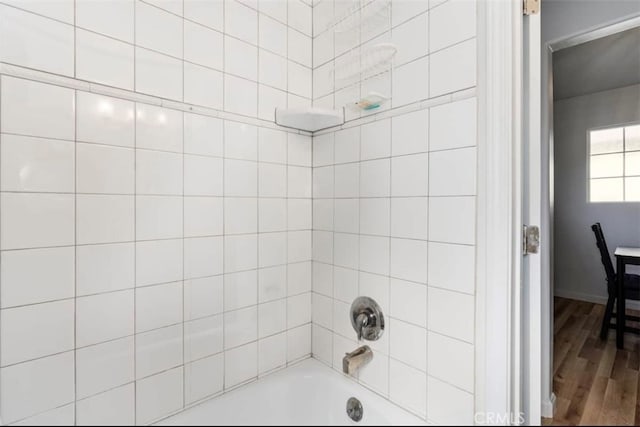 bathroom with tiled shower / bath combo and hardwood / wood-style flooring