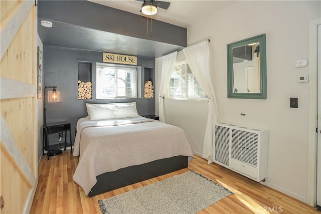 bedroom featuring wood-type flooring, radiator heating unit, and ceiling fan