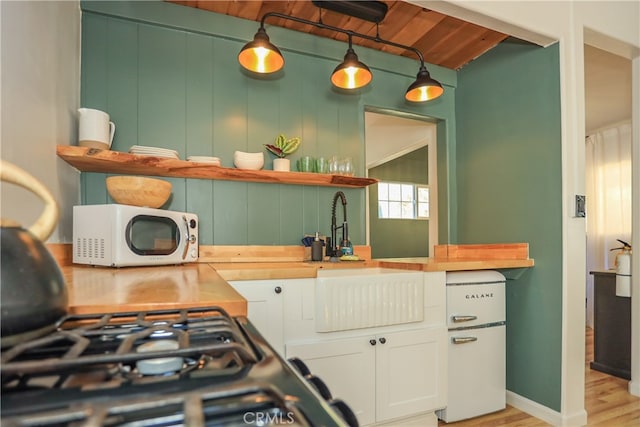 kitchen with wood ceiling, wood counters, decorative light fixtures, white cabinetry, and light hardwood / wood-style floors