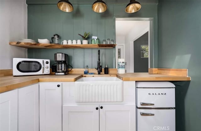 bar featuring sink, butcher block countertops, and white cabinets