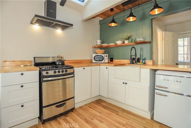 kitchen featuring white appliances, wood counters, decorative light fixtures, light hardwood / wood-style flooring, and exhaust hood